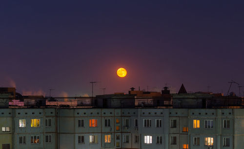 Windows, roofs and facade of an mass apartment buildings in russia at full moon night. 