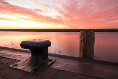 Pier on lake against sky during sunset