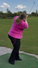 Side view of girl standing on pink umbrella