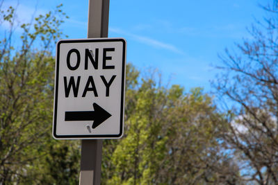 One way road sign against trees