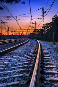 Surface level of railroad tracks against sky during sunset