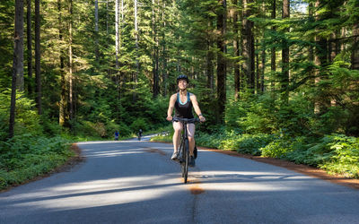 Man standing on road amidst trees in forest