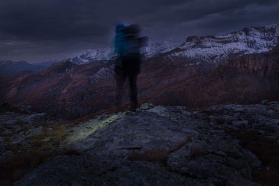 Rear view of man standing on mountain against sky