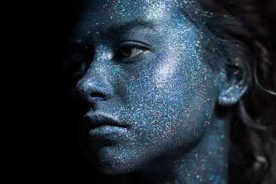 Close-up portrait of a serious young woman with blue face 