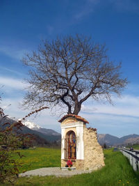 Built structure by tree against sky