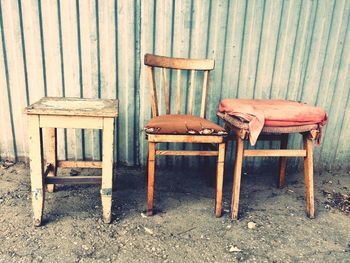 Abandoned chair and tables against corrugated iron