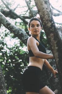 Side view of teenage girl looking away while exercising against trees in park