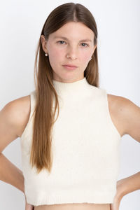 Portrait of young woman standing against white background