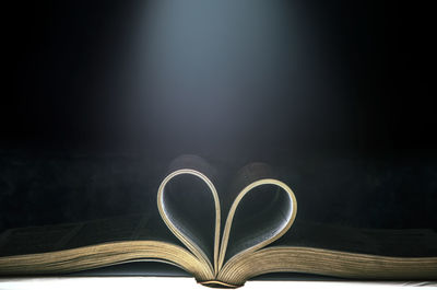 Close-up of heart shape on book against black background