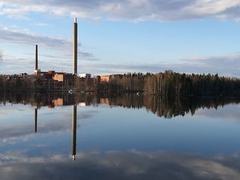 Reflection smoke stack in lake against sky