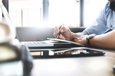 Midsection of woman using mobile phone while sitting on table