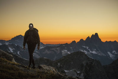 Hiker ascends mountain using headlamp after sunset.