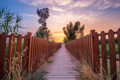 Wooden posts on field against sky at sunset