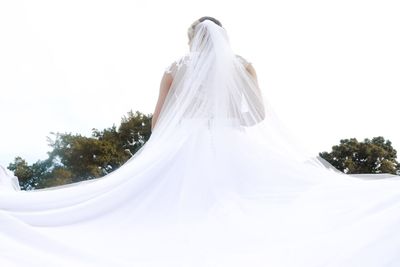 Rear view of woman with white umbrella against sky