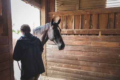 Rear view of man with horse at stable
