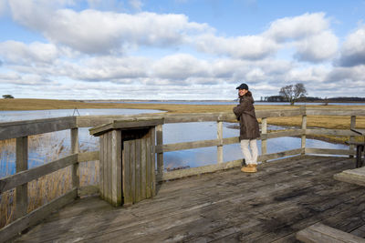 Portrait of woman standing by railing against sky