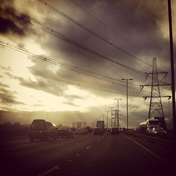 transportation, sky, car, cloud - sky, road, land vehicle, mode of transport, cloudy, the way forward, street, sunset, electricity pylon, cloud, diminishing perspective, power line, weather, overcast, vanishing point, silhouette, outdoors