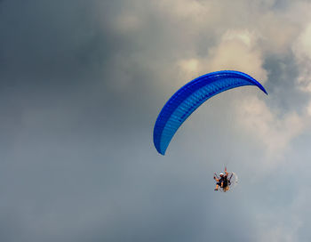 Low angle view of person paragliding against sky