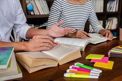 Midsection of woman reading book on table