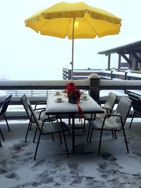 Chairs and table at cafe by sea against sky