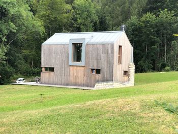 Barn on field against trees and house