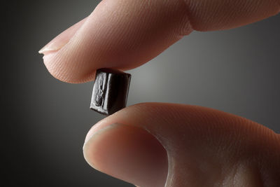 Close-up of hand holding metal against black background
