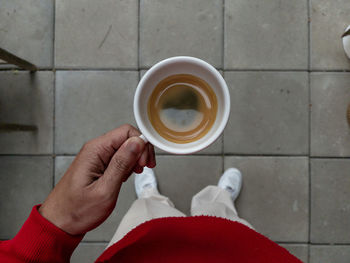 Midsection of person holding coffee cup on floor