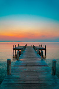 Wooden pier on sea against sky during sunset