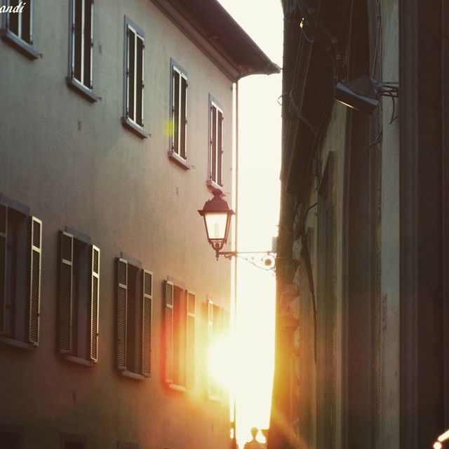 architecture, built structure, building exterior, building, residential building, window, residential structure, city, house, sunlight, low angle view, sunset, street, no people, outdoors, illuminated, street light, day, orange color, sky