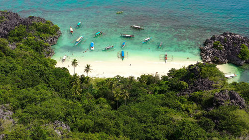 Lahos island with beautiful beach and tourists by turquoise water. caramoan islands, philippines. 