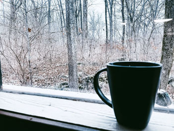 Coffee cup on table by tree during winter