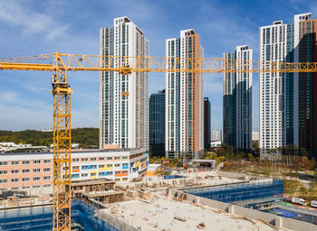 Construction site by buildings against sky in city