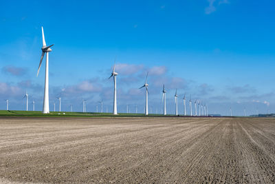 Wind turbines on field against sky