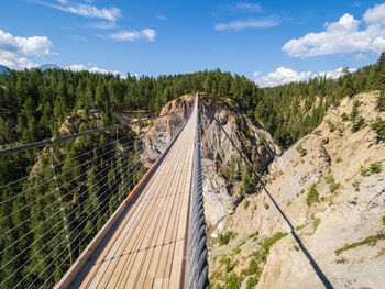 High angle view of wooden suspension bridge over a canyon against sky