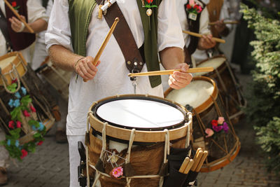 Midsection of people playing drum on street