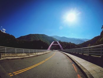 Road by bridge against clear blue sky