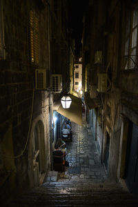 Narrow alley amidst buildings in city at night