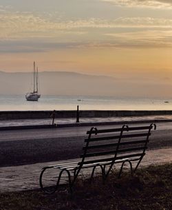 Deck chairs on beach against sky during sunset