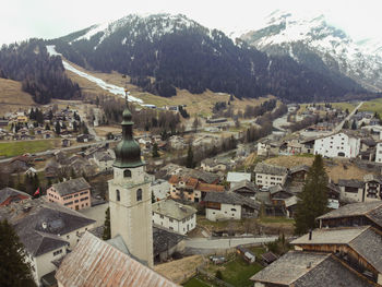 High angle view of townscape by snowcapped mountains against sky