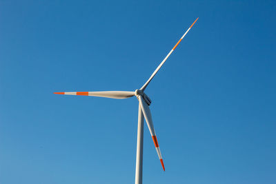 Low angle view of wind turbine against blue sky