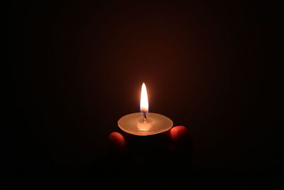 Close-up of lit candle against black background