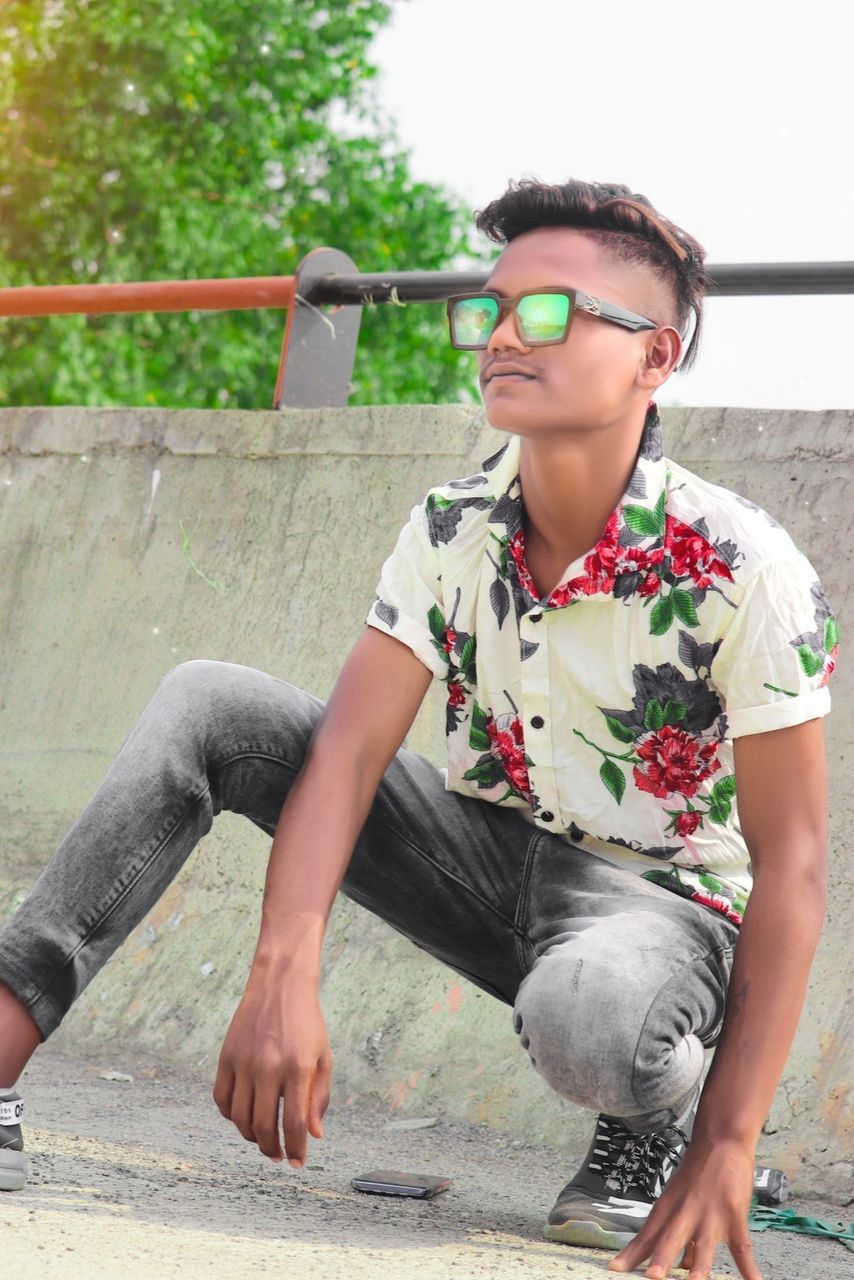 one person, glasses, fashion, young adult, sitting, leisure activity, casual clothing, full length, sunglasses, lifestyles, adult, photo shoot, day, nature, front view, eyeglasses, women, outdoors, architecture, looking, relaxation, portrait, city, cool attitude, child, spring, person, hairstyle, clothing, skateboard, smiling, childhood, enjoyment, looking away, happiness, black hair, individuality