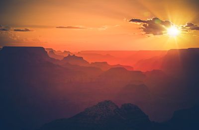 Scenic view of silhouette mountains against orange sky