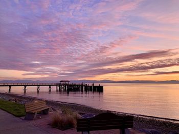 Pier over sea against orange sky