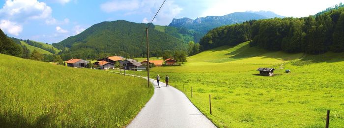 People walking on grassy field against mountain