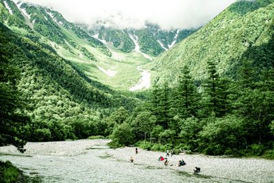 High angle view of people by river and mountains