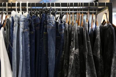 Jeans, t-shirts and casual shirts are hanging on the clothesline in a shopping mall.