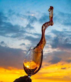 Close-up of frozen splash of wine against sky during sunset