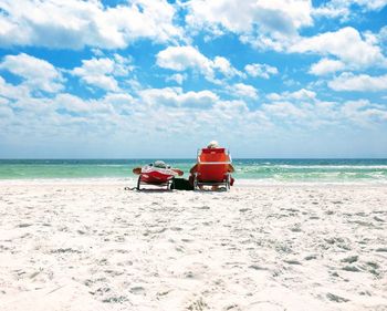 Couple lounging on beach against sky