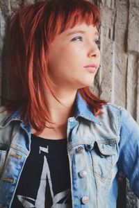 Beautiful redhead young woman looking away against wall